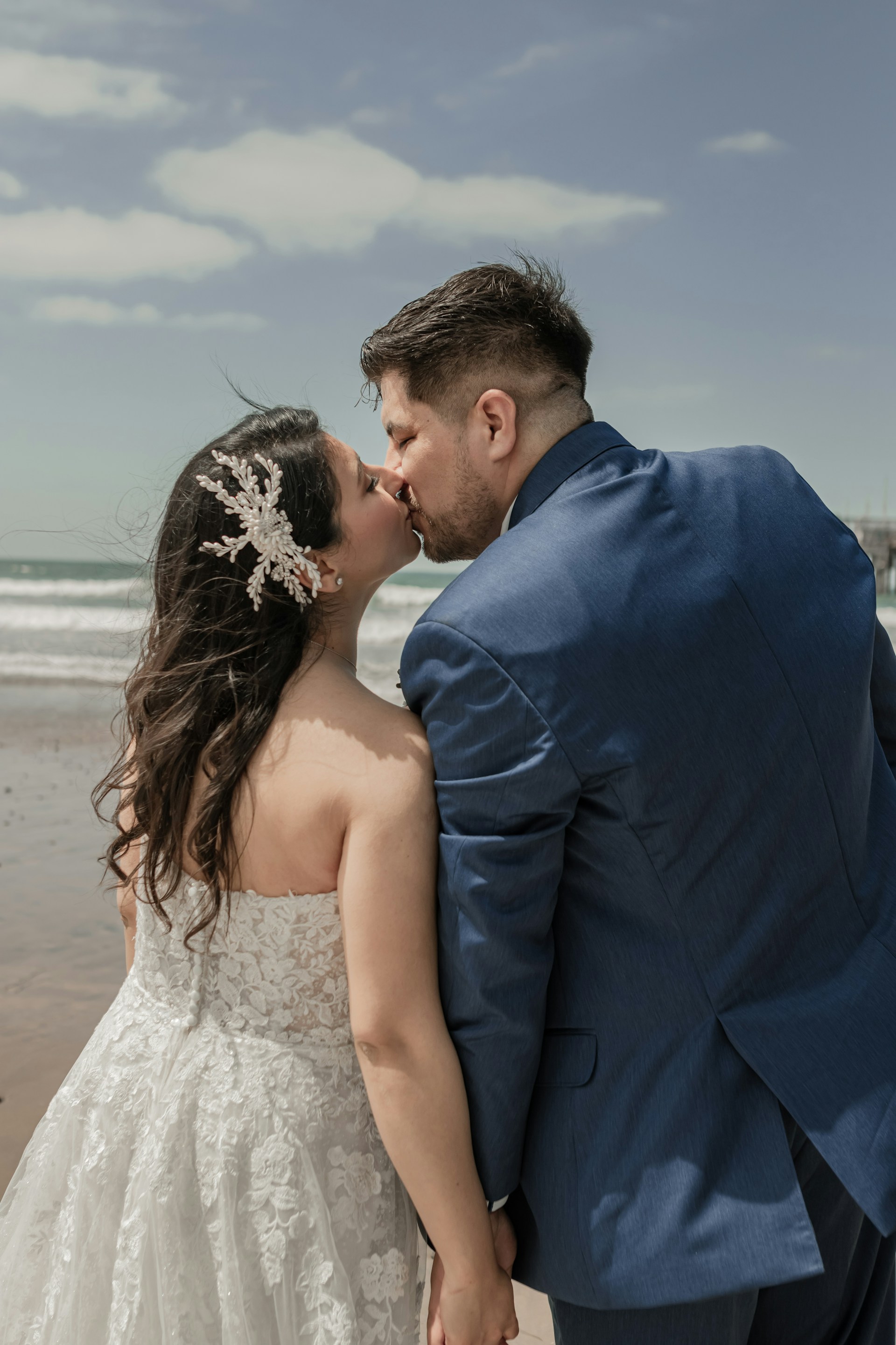 a bride and groom kissing on the beach