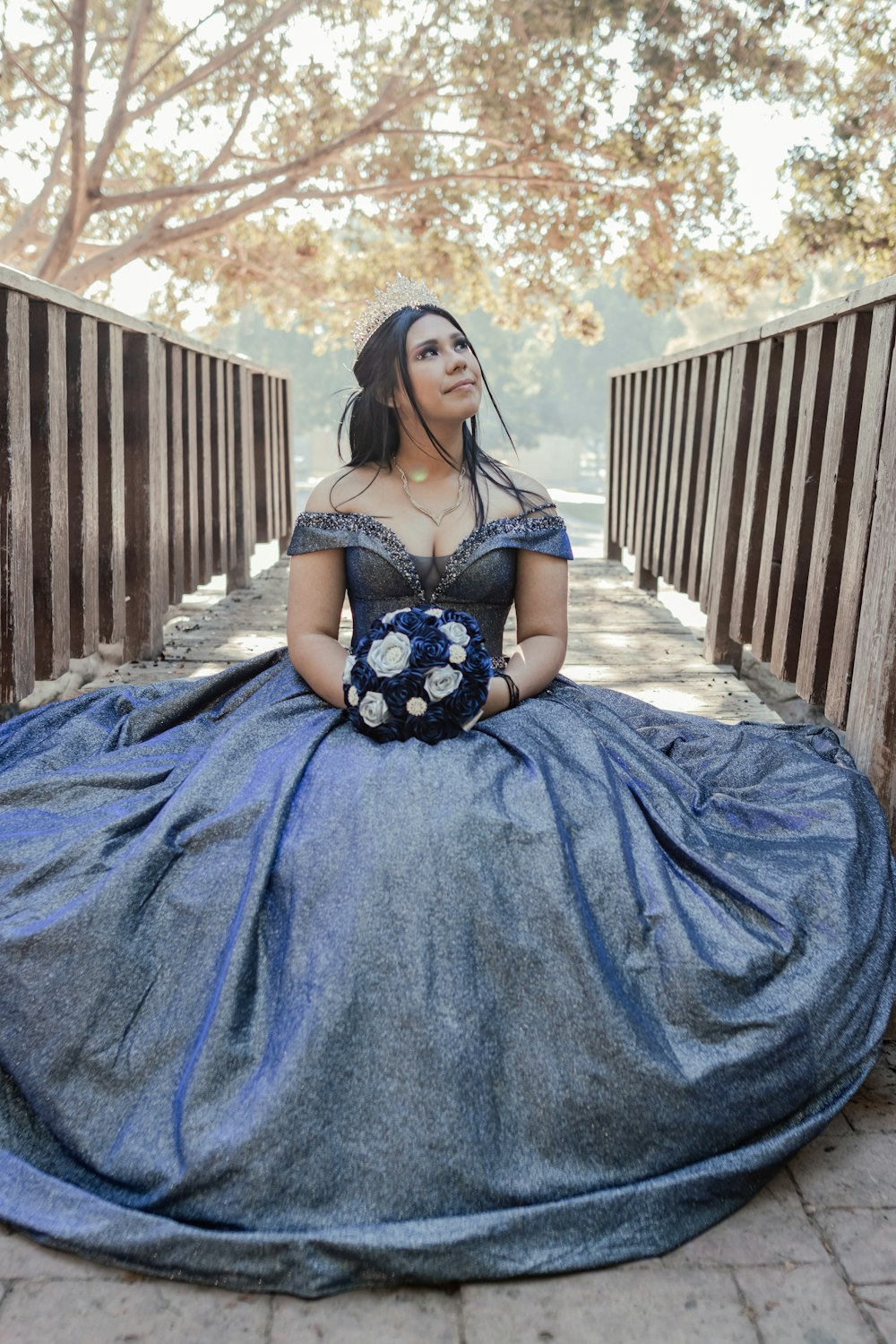 a woman in a blue dress sitting on a wooden bench