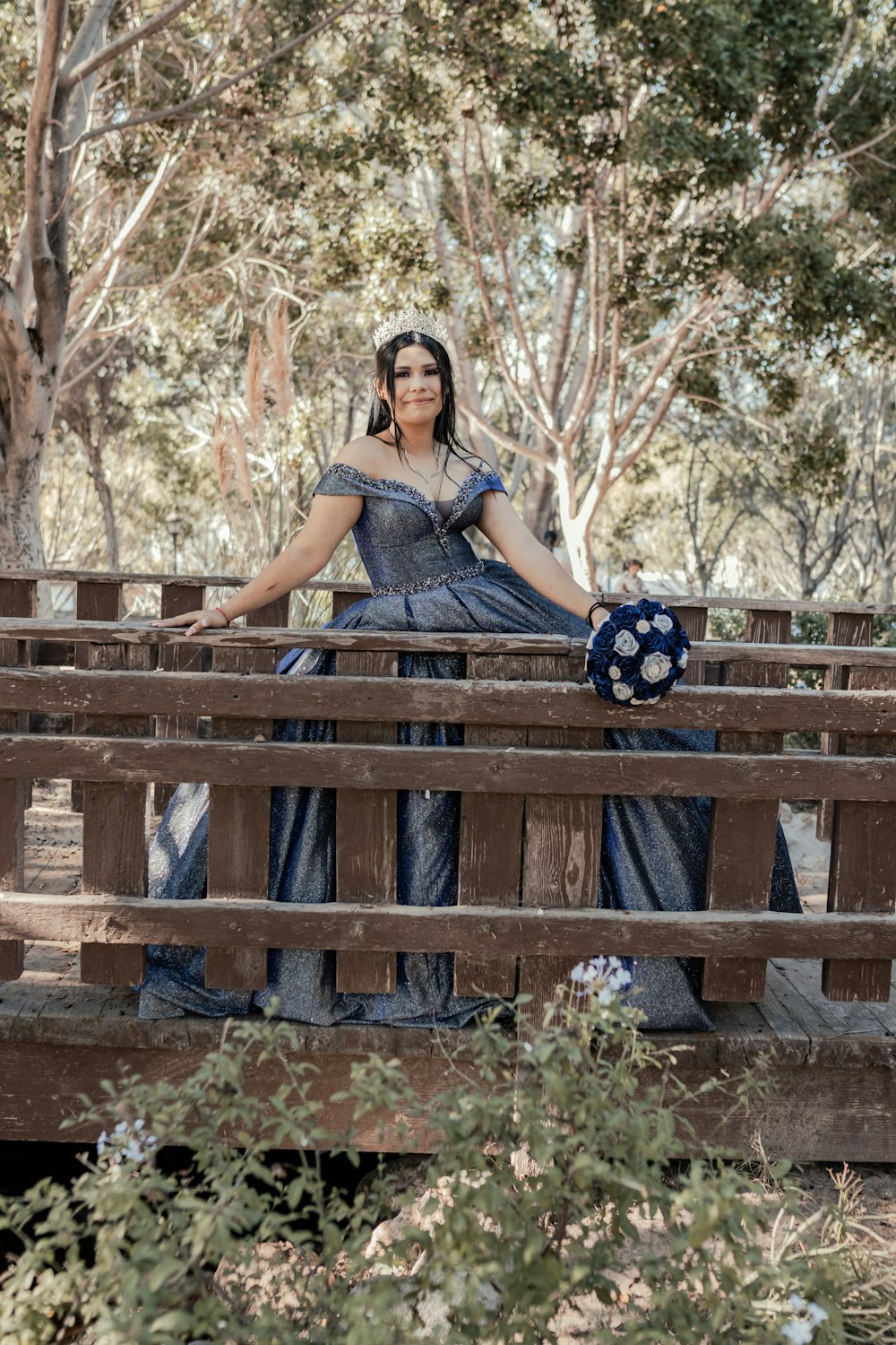 a woman in a blue dress sitting on a wooden bench