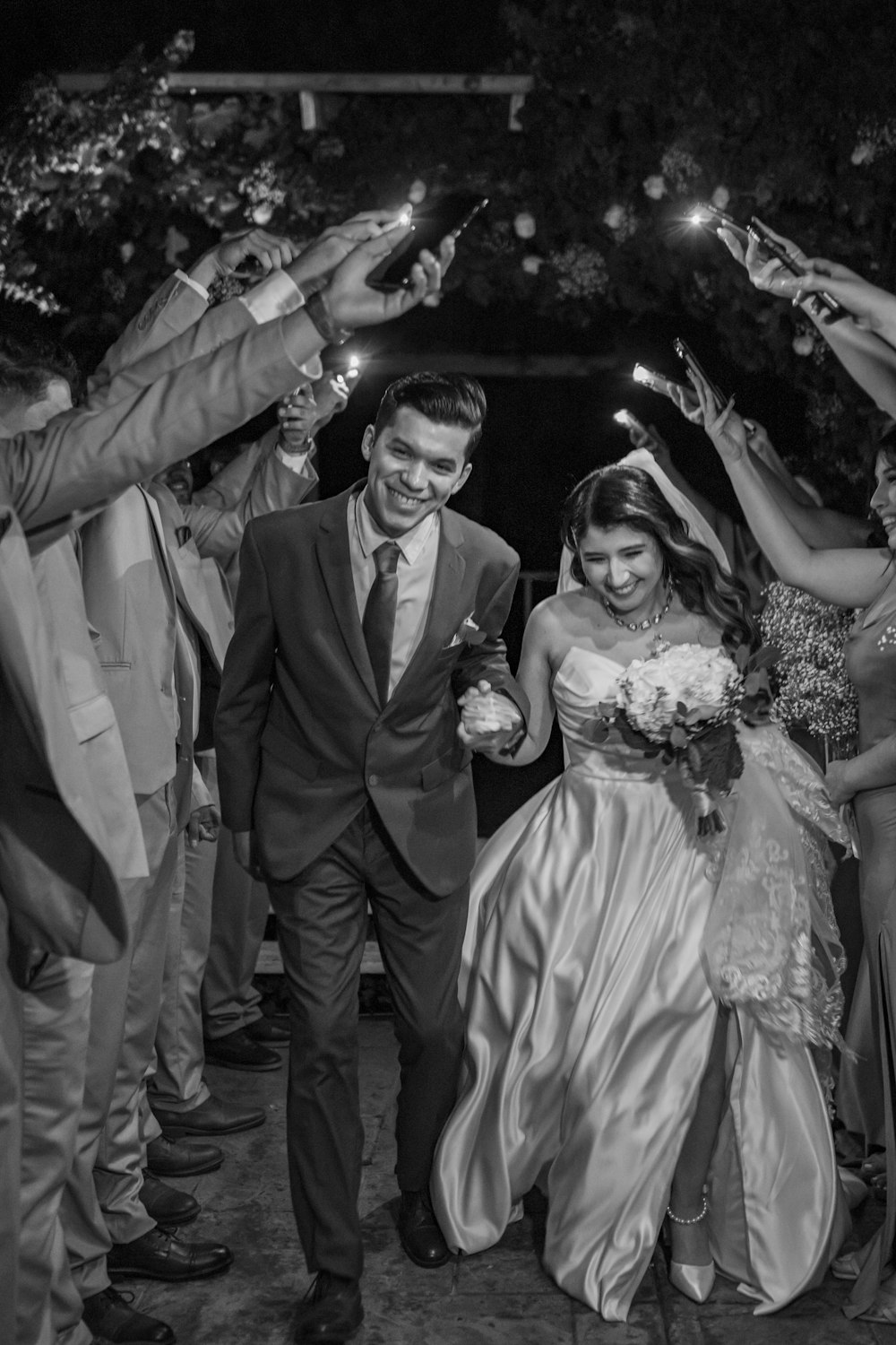 a bride and groom walking through a crowd of people holding sparklers