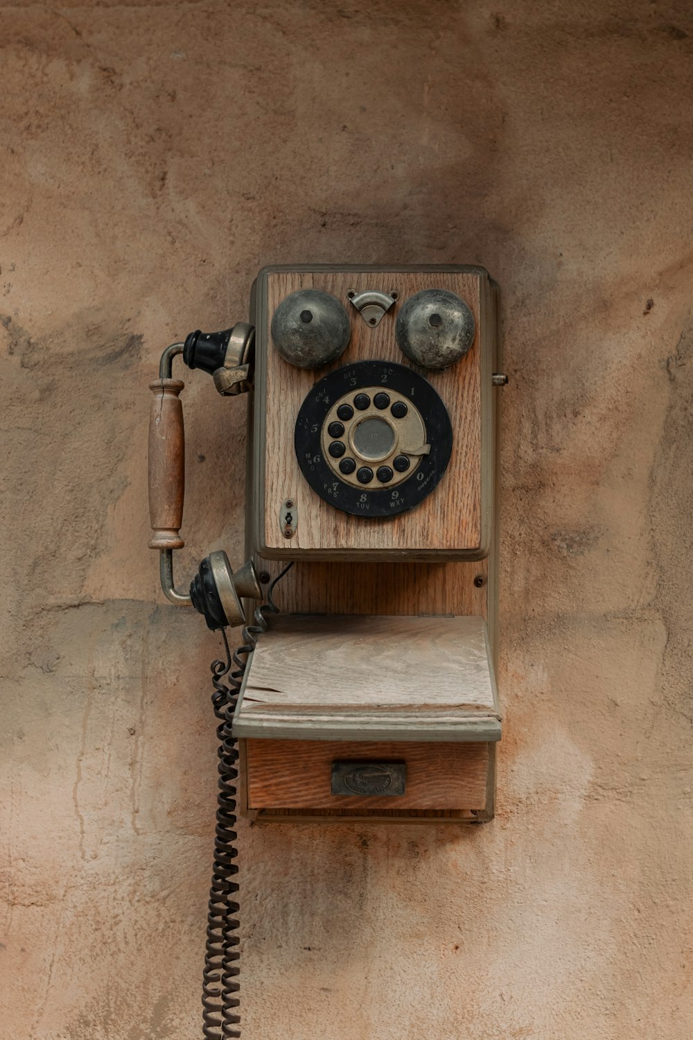 an old fashioned wooden phone mounted to a wall