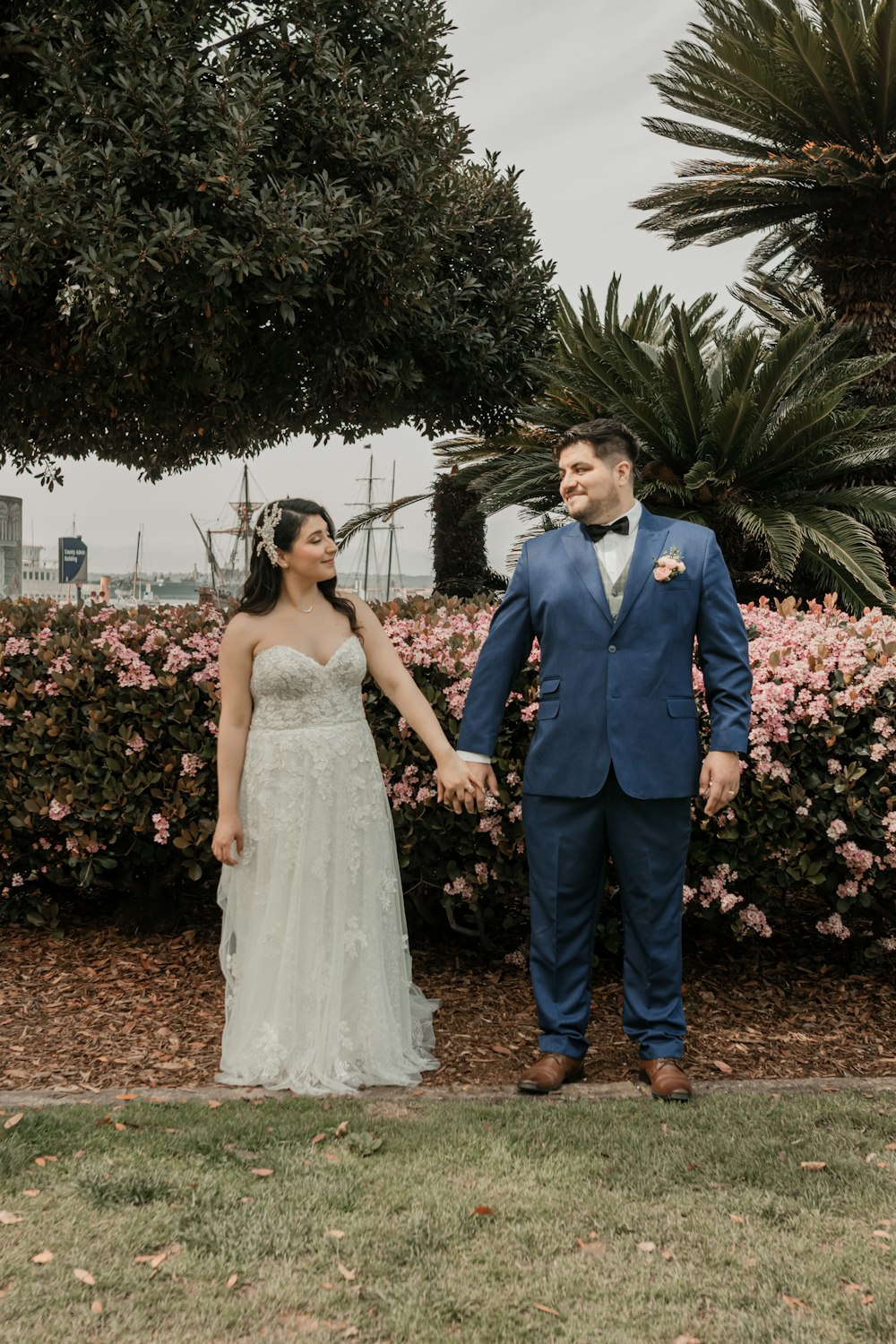 a bride and groom holding hands in front of a bush