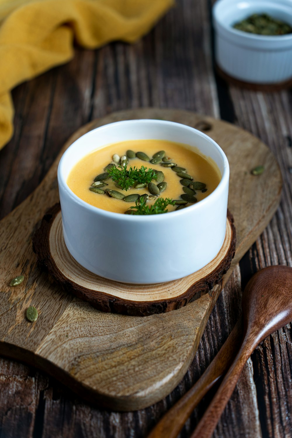 un cuenco blanco lleno de sopa encima de una tabla de cortar de madera