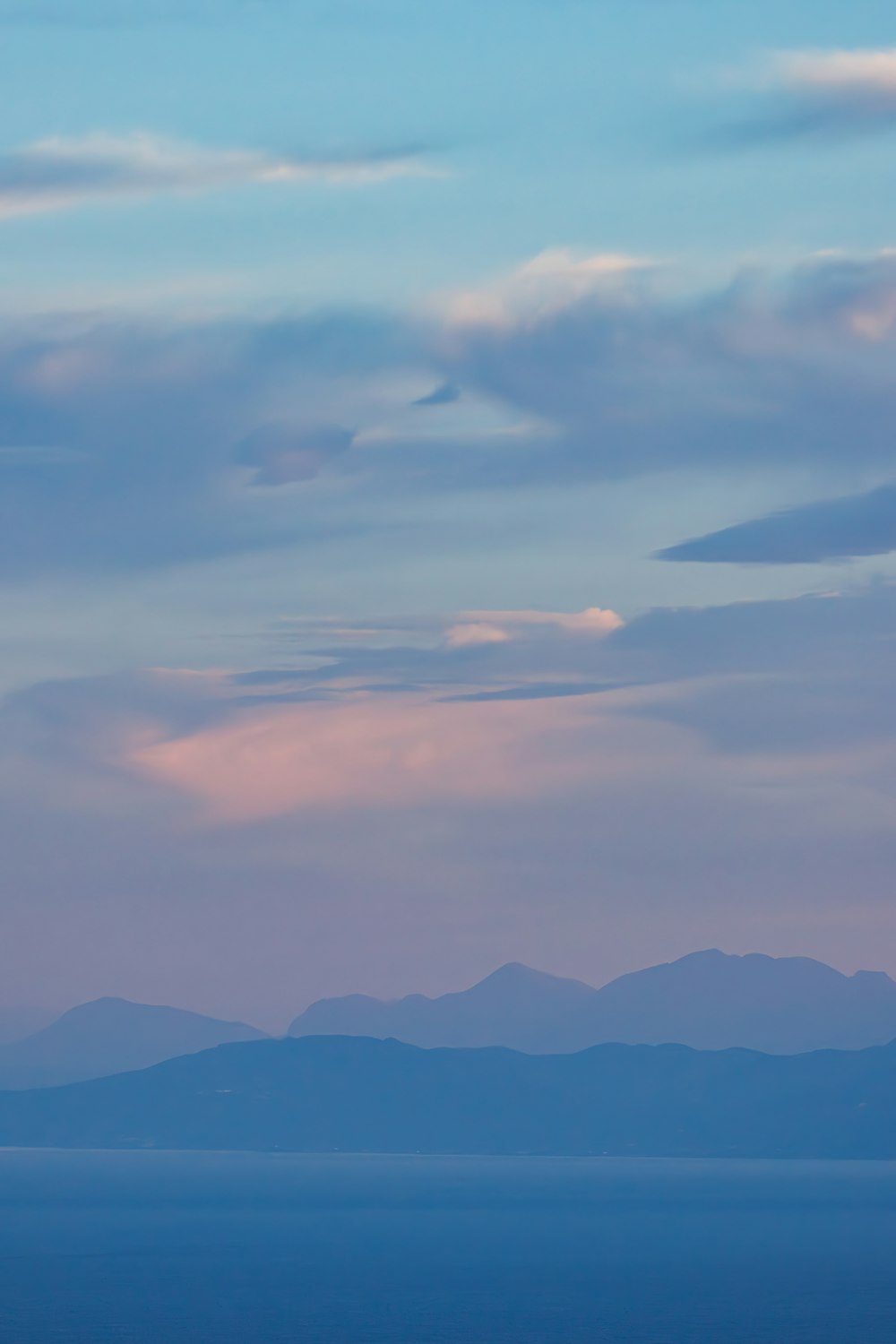 a plane flying in the sky with mountains in the background