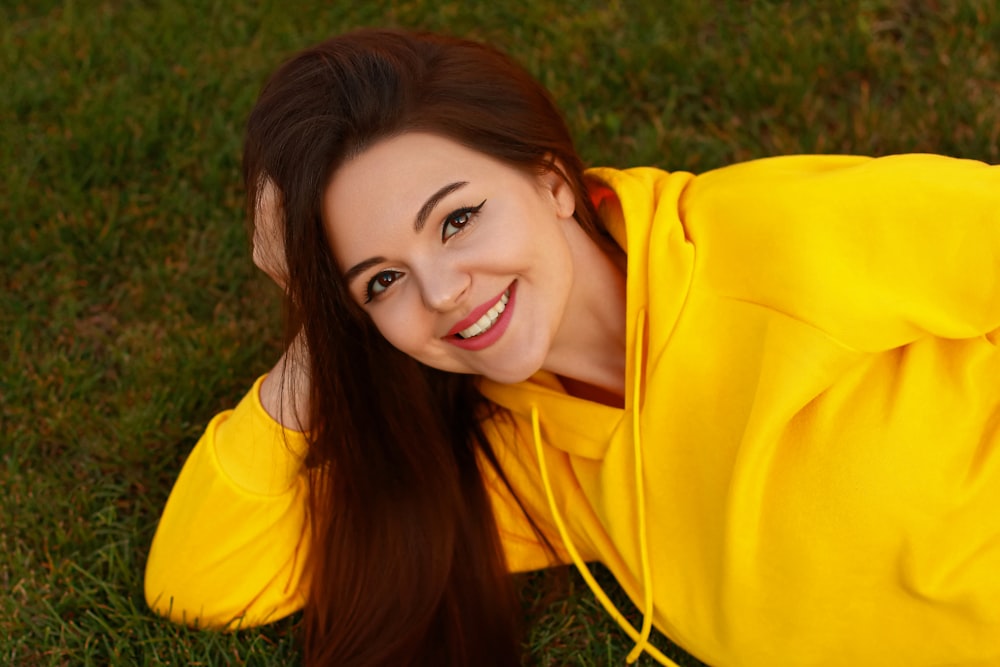 a woman in a yellow shirt laying on the grass