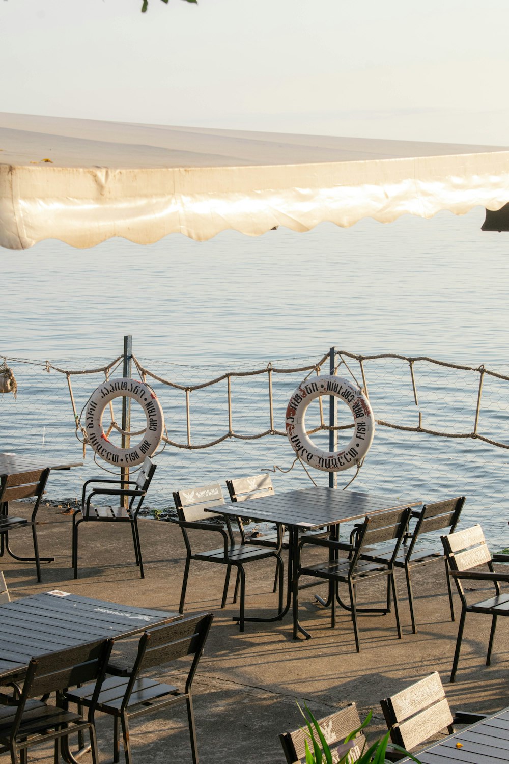 tables and chairs on a pier near the water