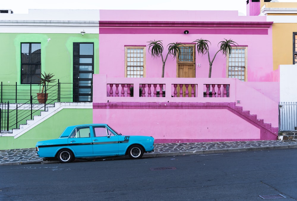 a blue car parked in front of a multi - colored building