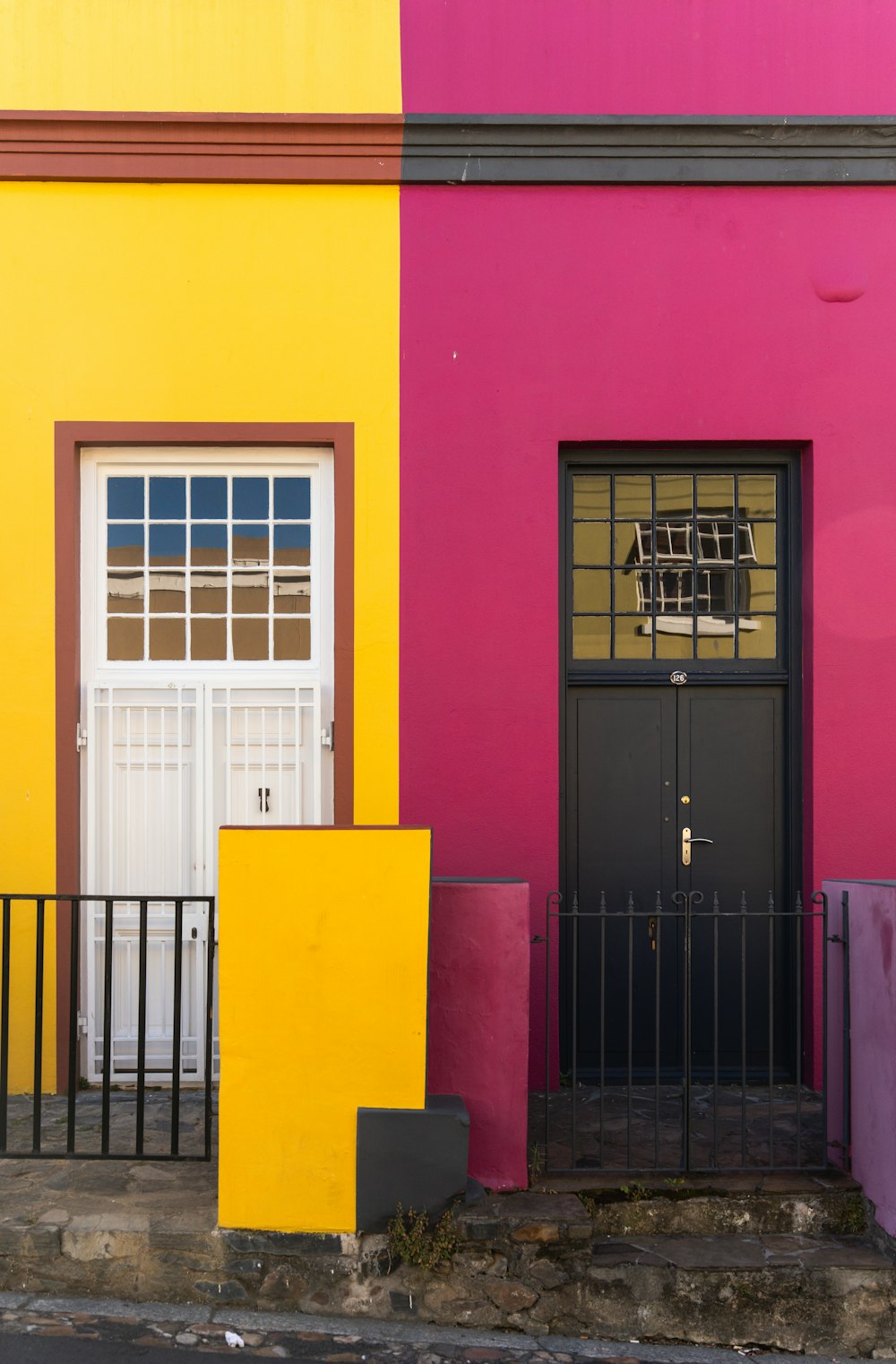 a yellow and pink building with a black gate