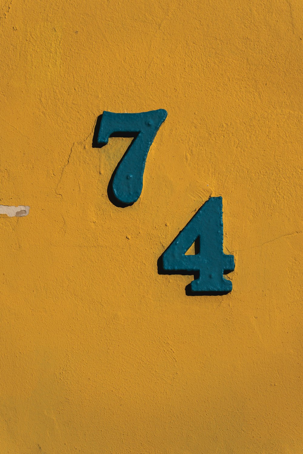 a blue number on the side of a yellow wall
