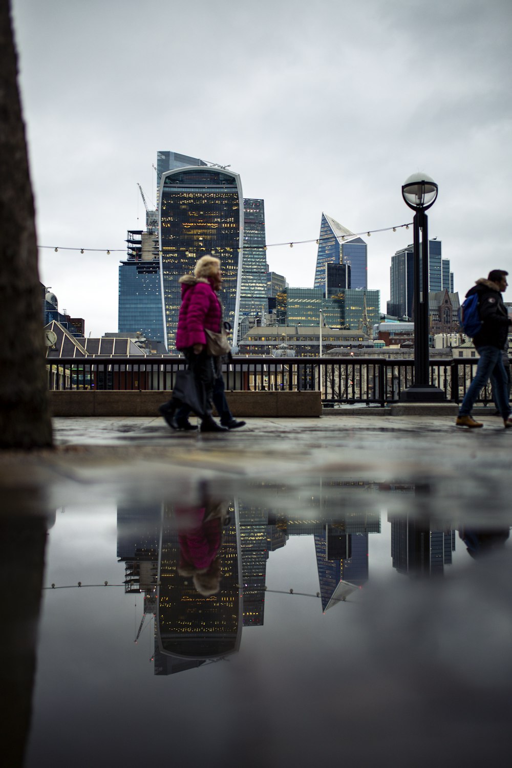 a group of people walking across a wet sidewalk