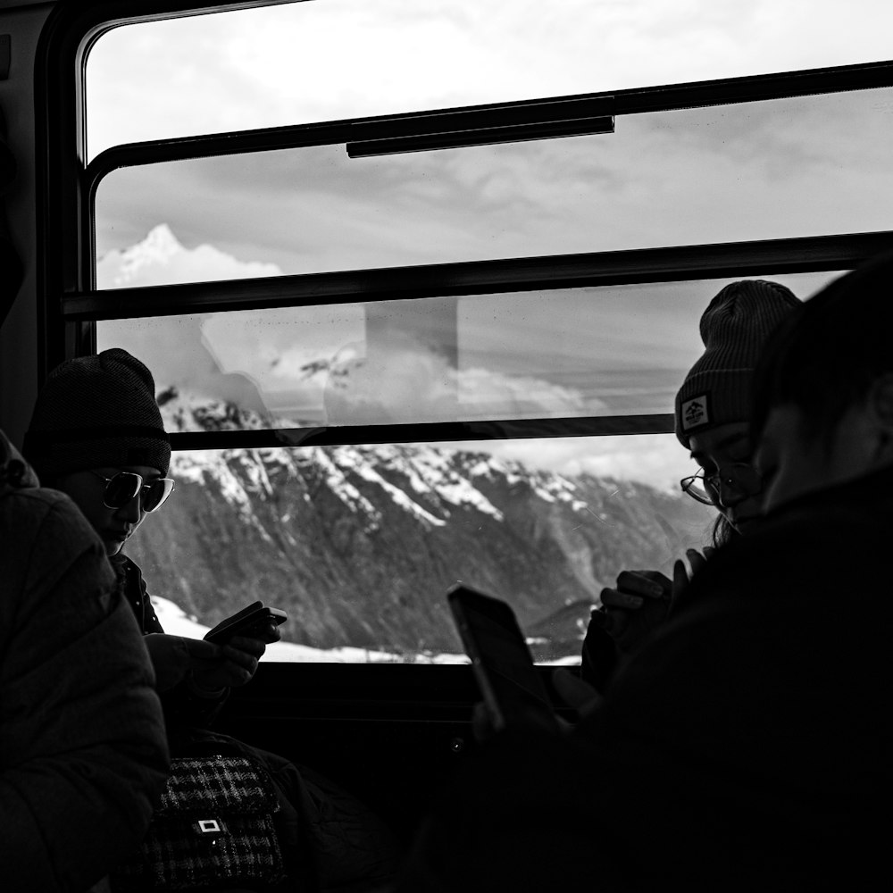 a group of people sitting on a bus looking at their cell phones