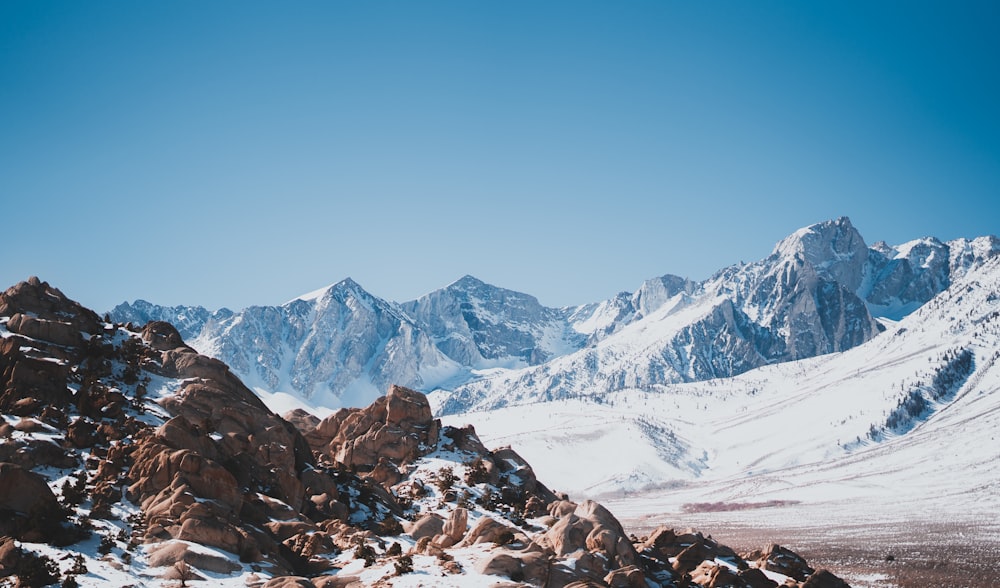 a mountain range covered in snow under a blue sky