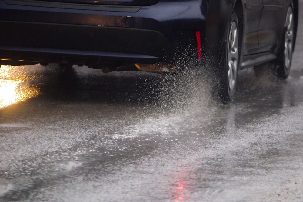 a car driving down a wet road next to a fire hydrant