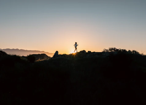 a person standing on top of a hill at sunset