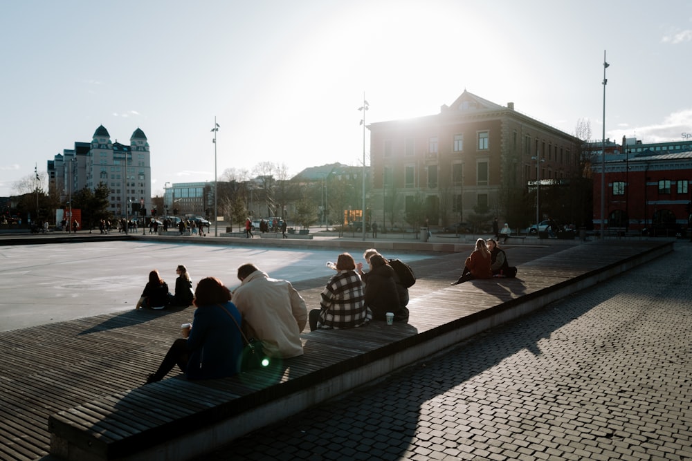 a group of people sitting on top of a sidewalk