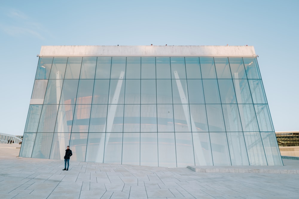 a man standing in front of a large glass building
