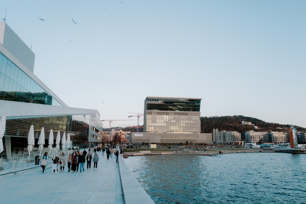 a group of people walking on a sidewalk next to a body of water