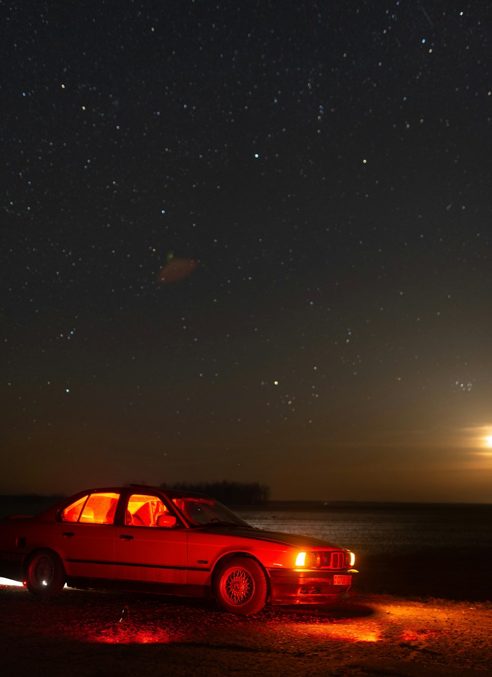 a red car parked on the side of the road at night