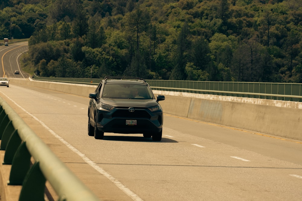 a car driving down a highway next to a forest