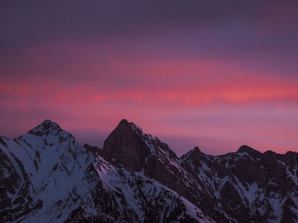 una cadena montañosa con un cielo rosado al fondo