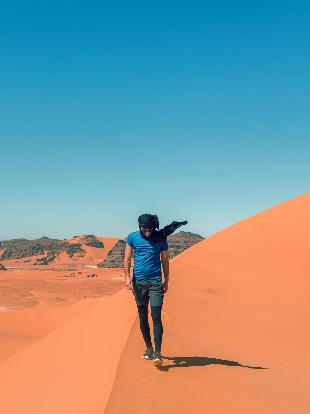 a man standing on top of a sand dune