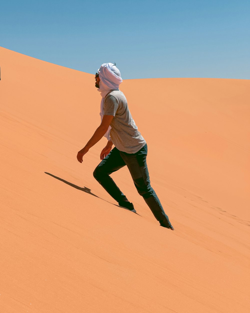a man riding a skateboard down the side of a sand dune