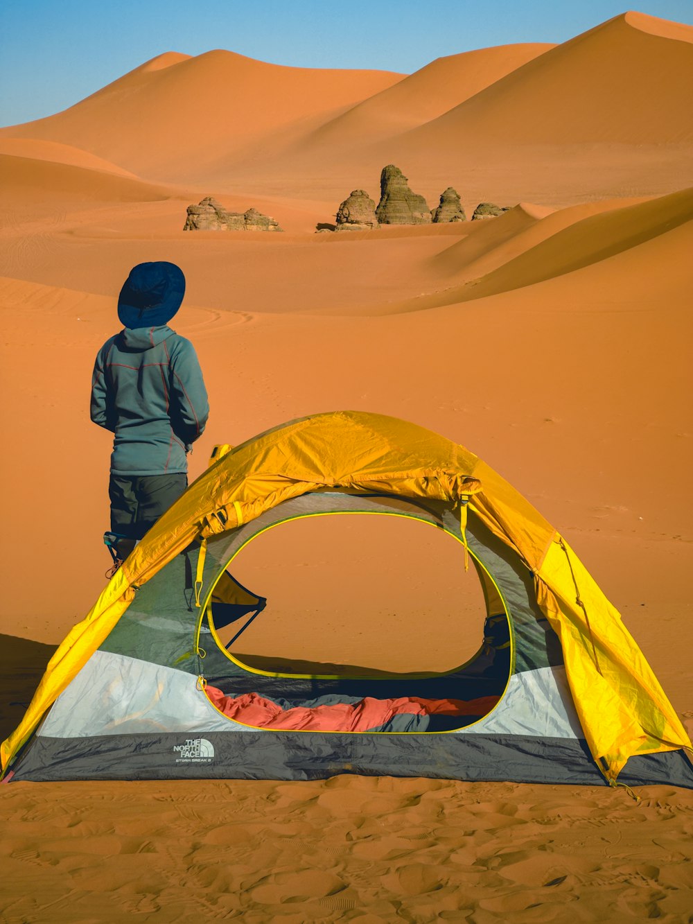 a person standing next to a tent in the desert
