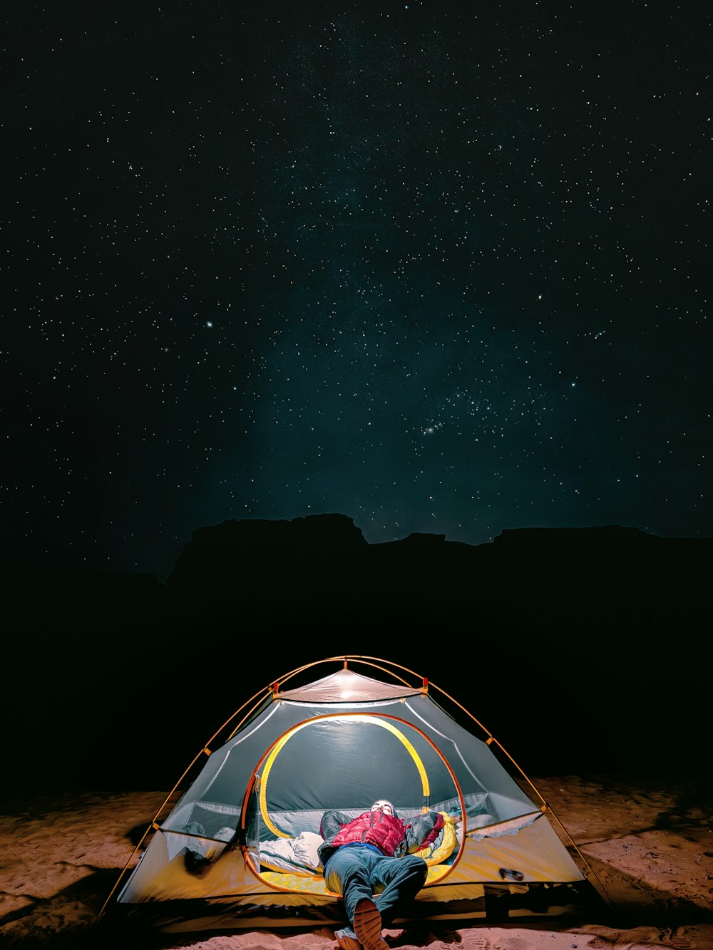 a man sitting inside of a tent under a night sky