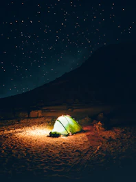 a green tent sitting on top of a sandy beach