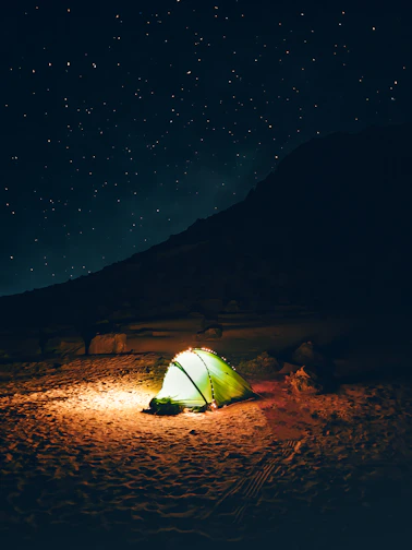 a green tent sitting on top of a sandy beach