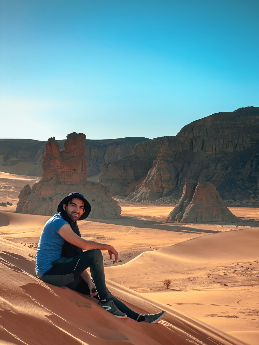 a man sitting on top of a sand dune