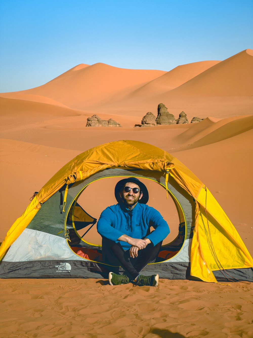 a man sitting inside of a tent in the desert