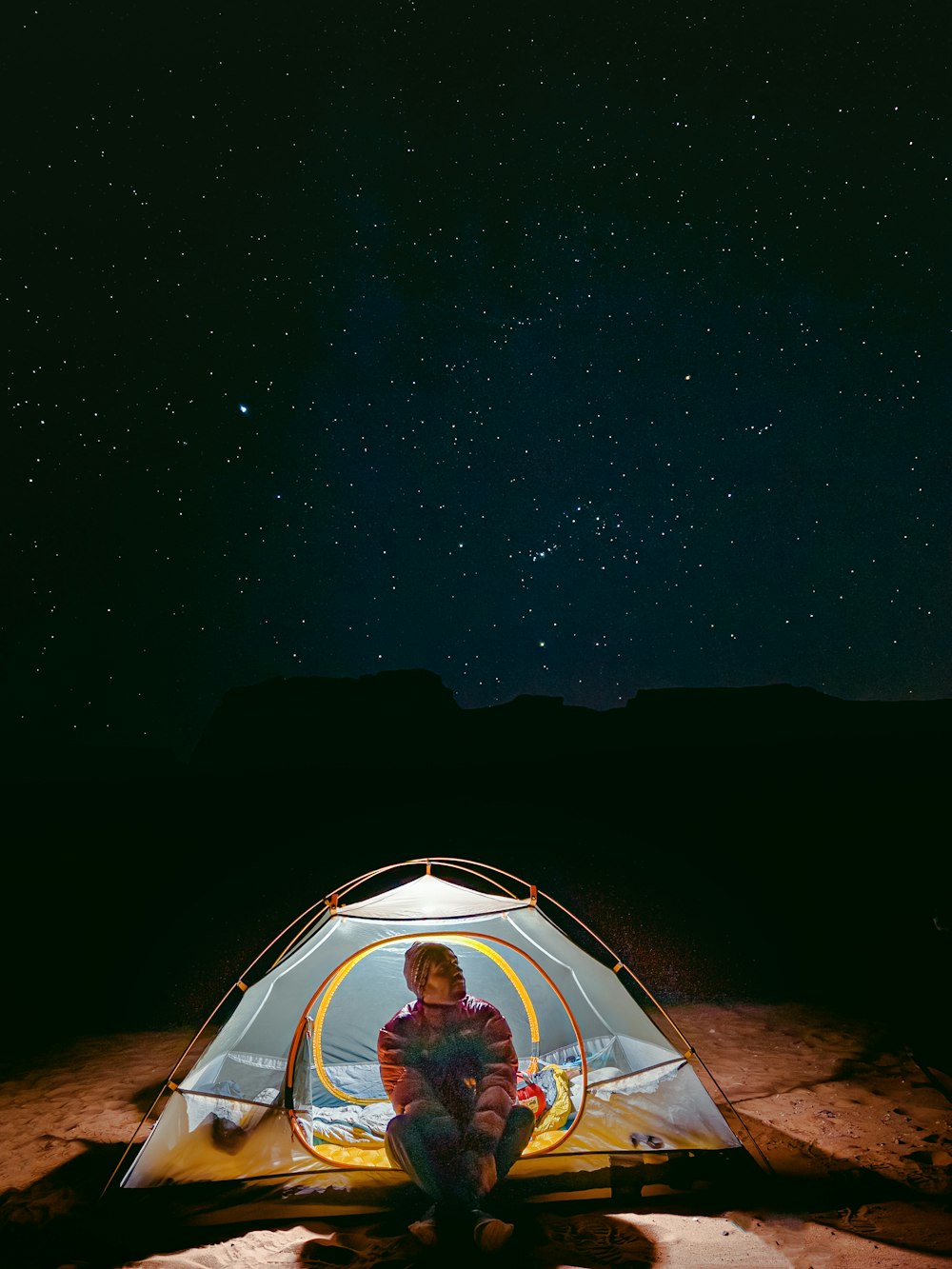 a man sitting inside of a tent under a night sky