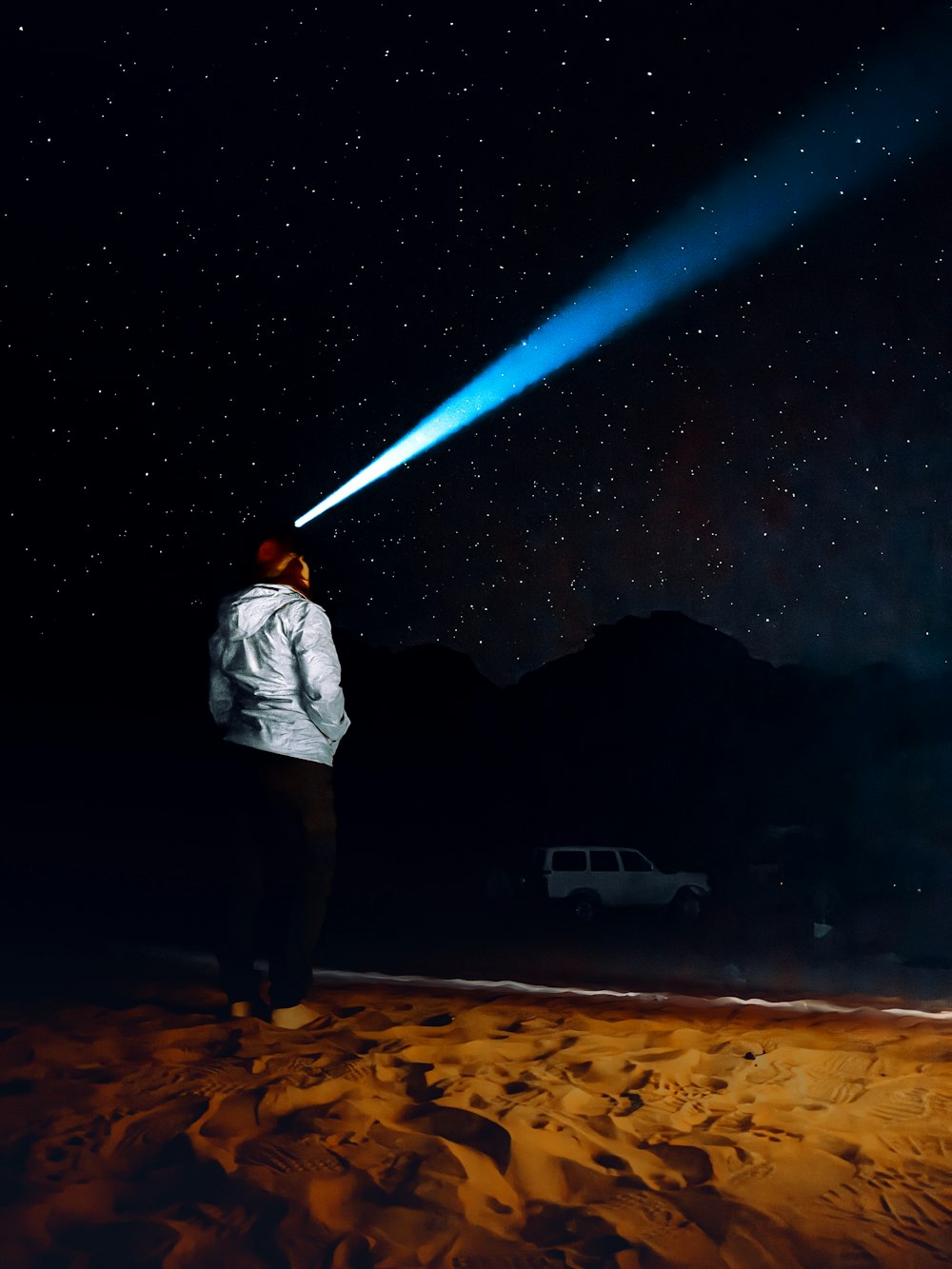 a man standing in the sand looking at the stars