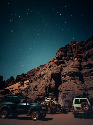 Campement dans la Tadrart Rouge, avec des véhicules 4x4 stationnés sous les montagnes et un bivouac 
