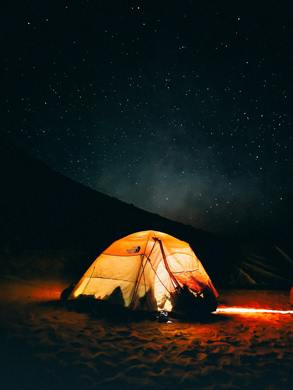 a tent is lit up at night in the desert