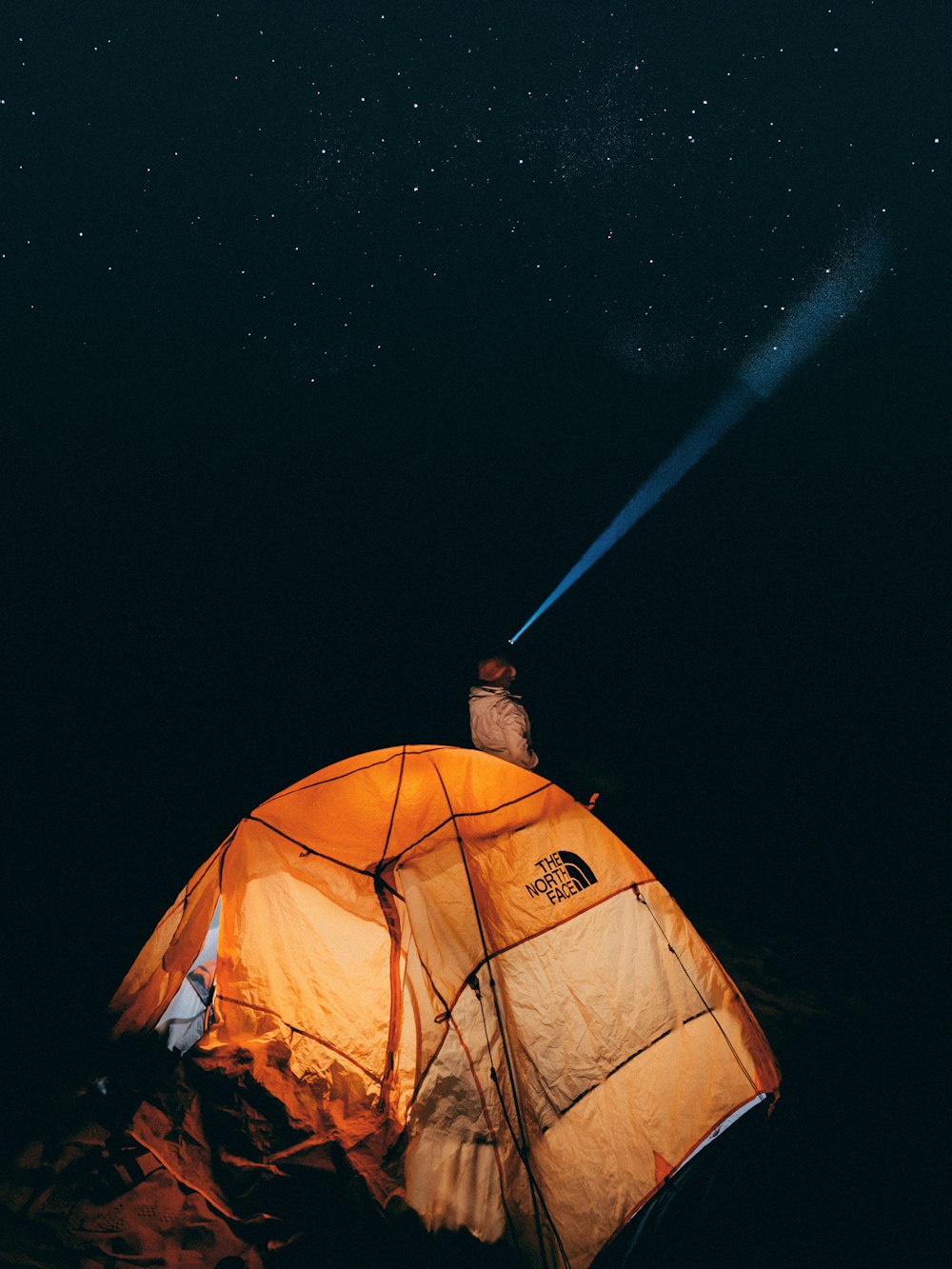 a person standing in front of a tent at night