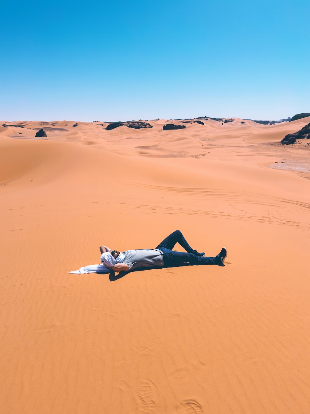 a man laying on top of a sandy beach