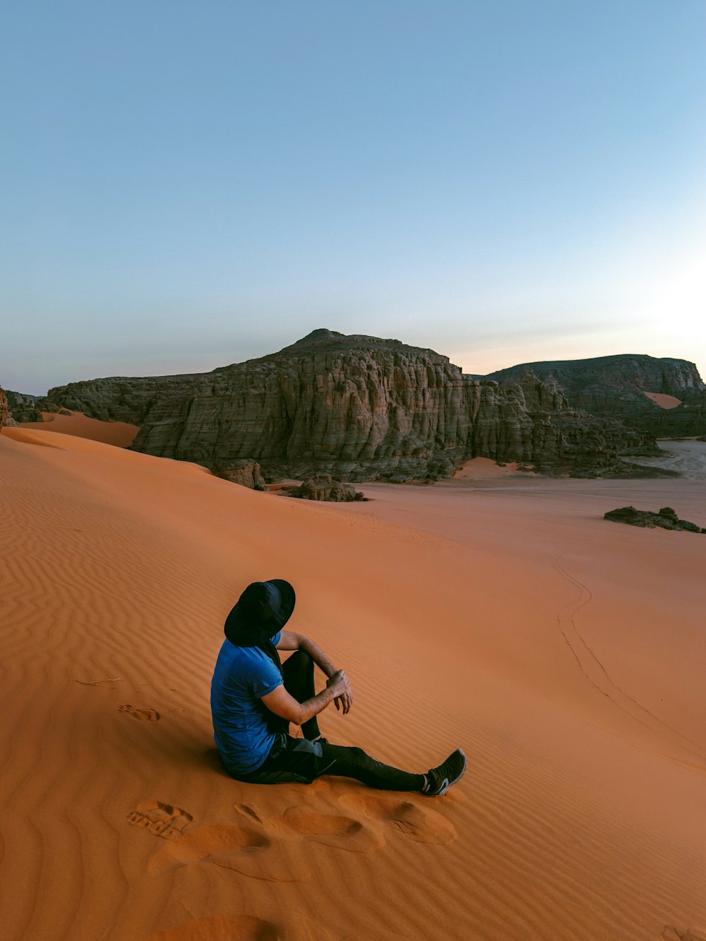 a man sitting on top of a sandy dune