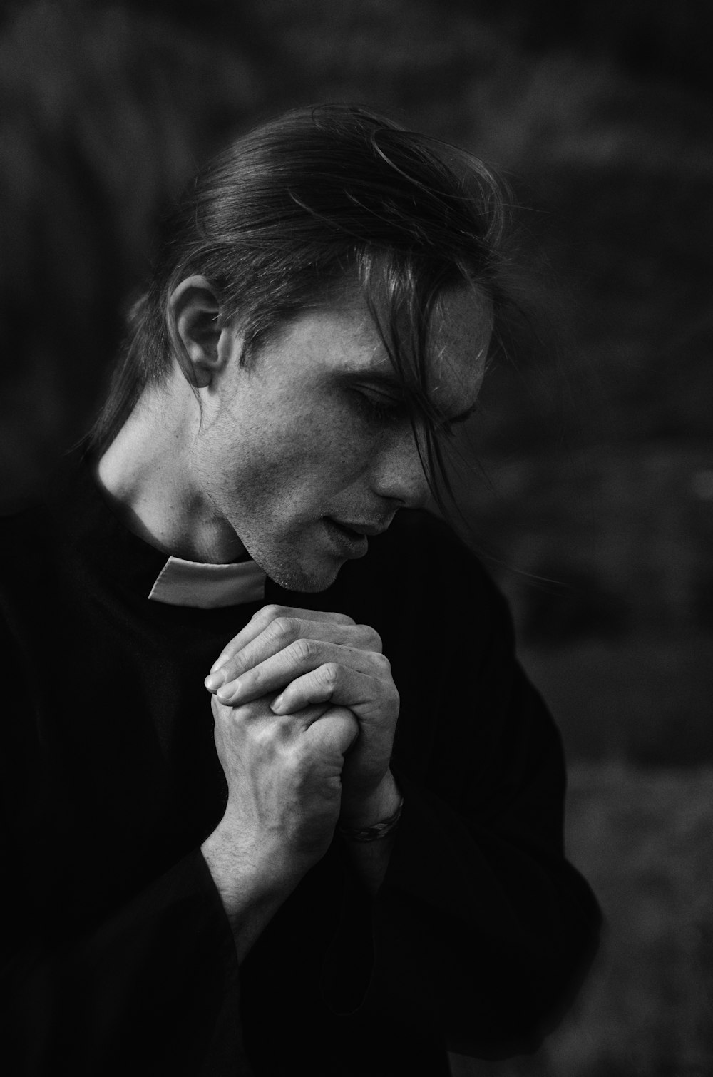 a black and white photo of a man holding his hands together