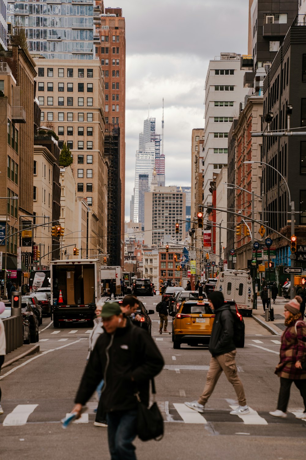 a group of people walking across a street next to tall buildings