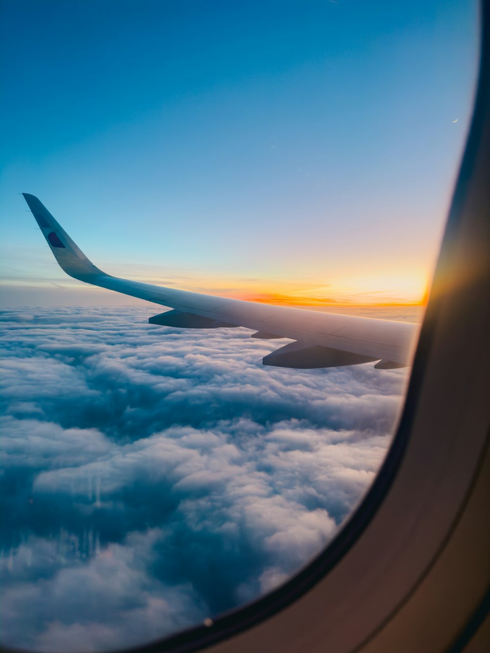 a view of the wing of an airplane as it flies above the clouds