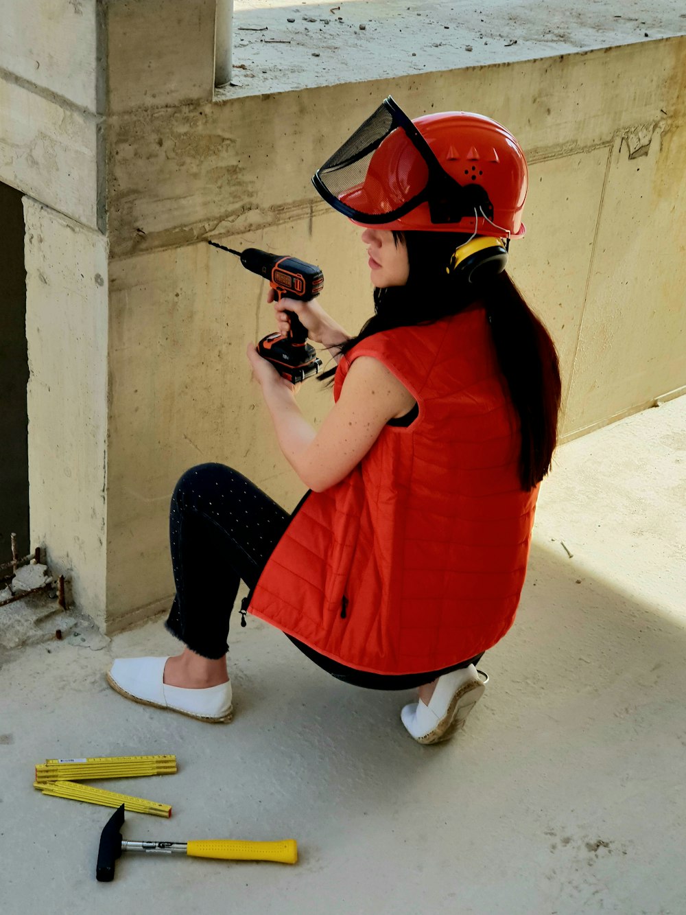 a woman sitting on the ground holding a drill