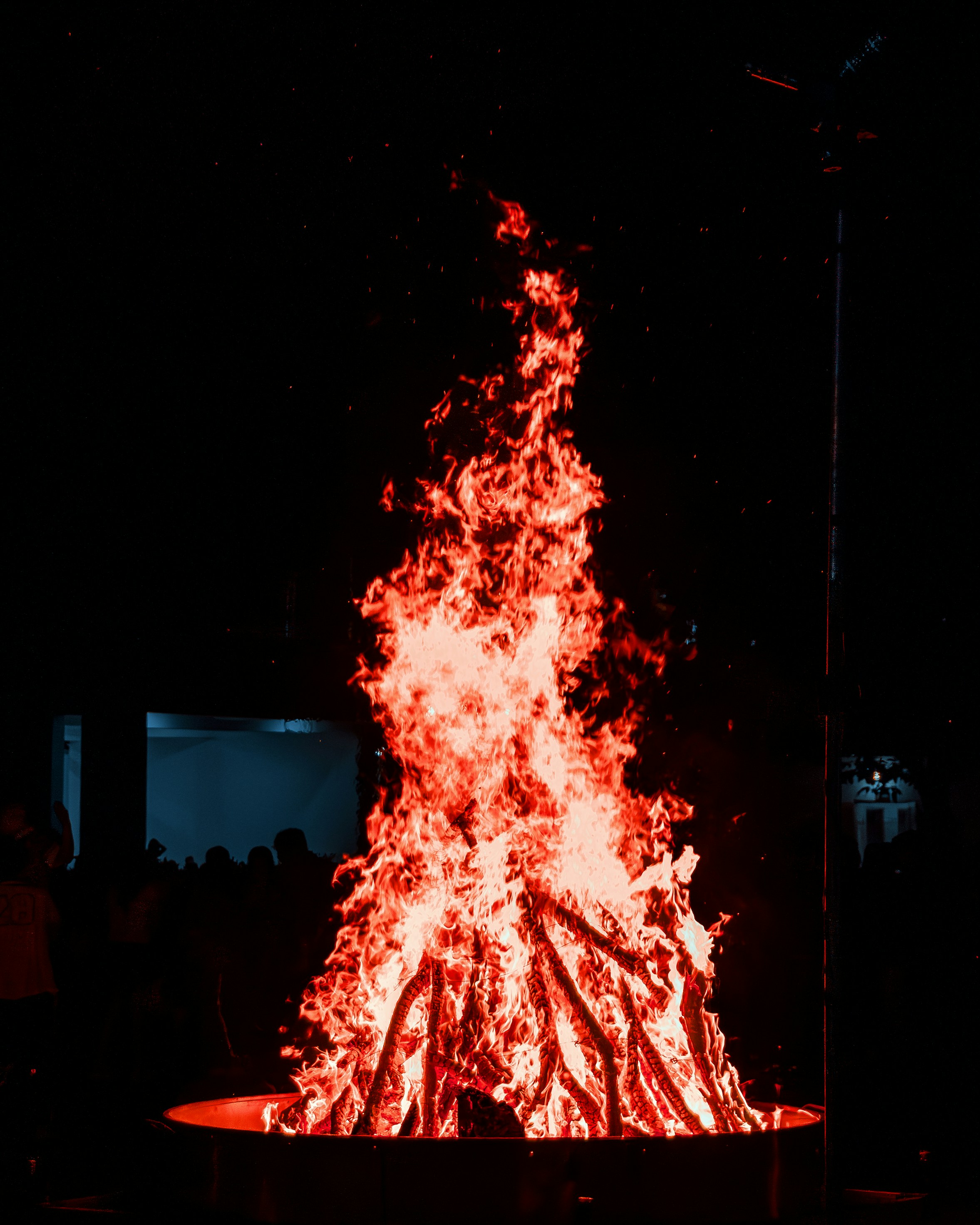 A large fire pit in the dark with people around it photo – Free Fire ...