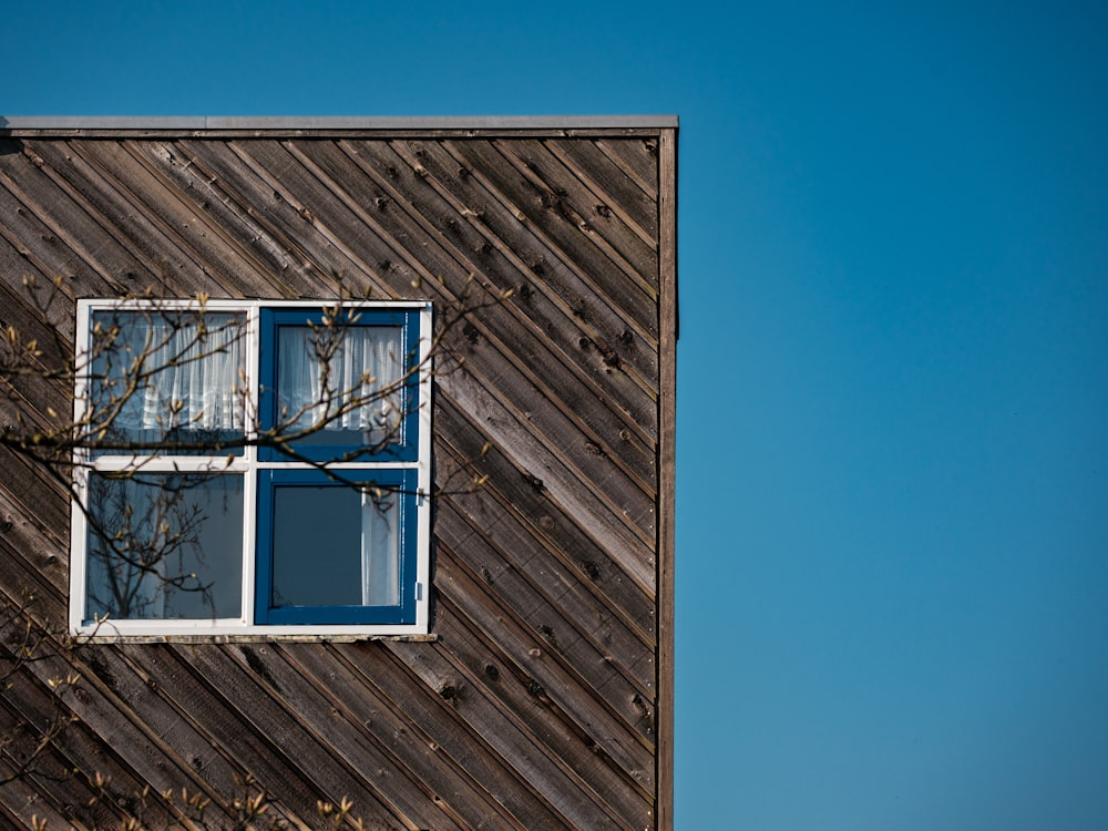um edifício de madeira com uma janela e uma árvore à sua frente