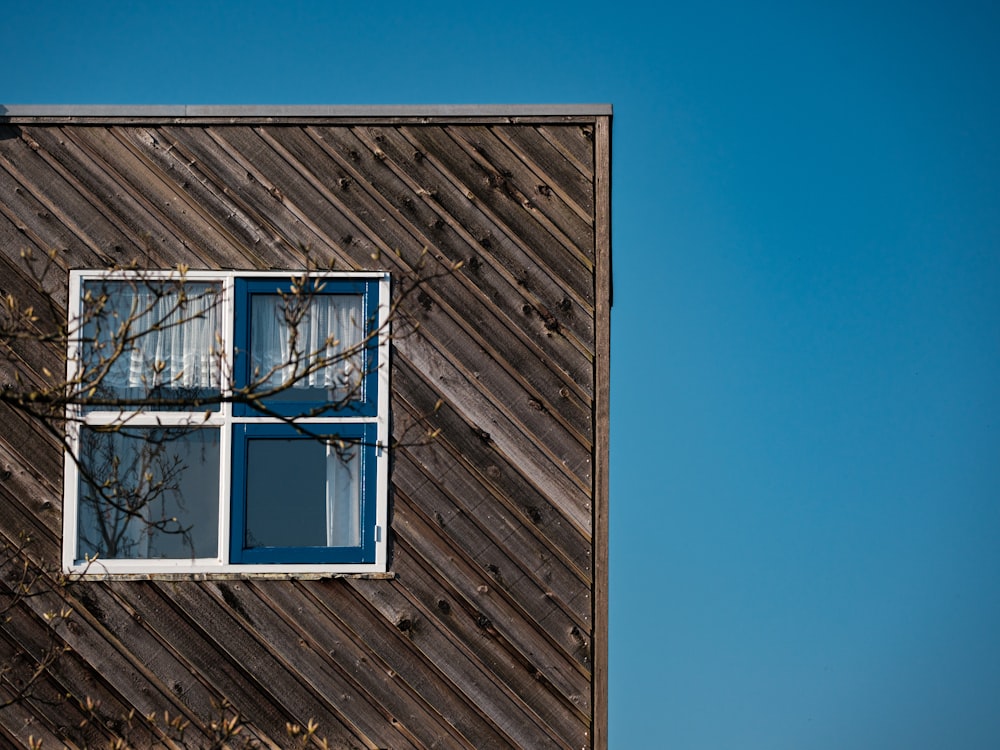 a wooden building with a window and a tree in front of it