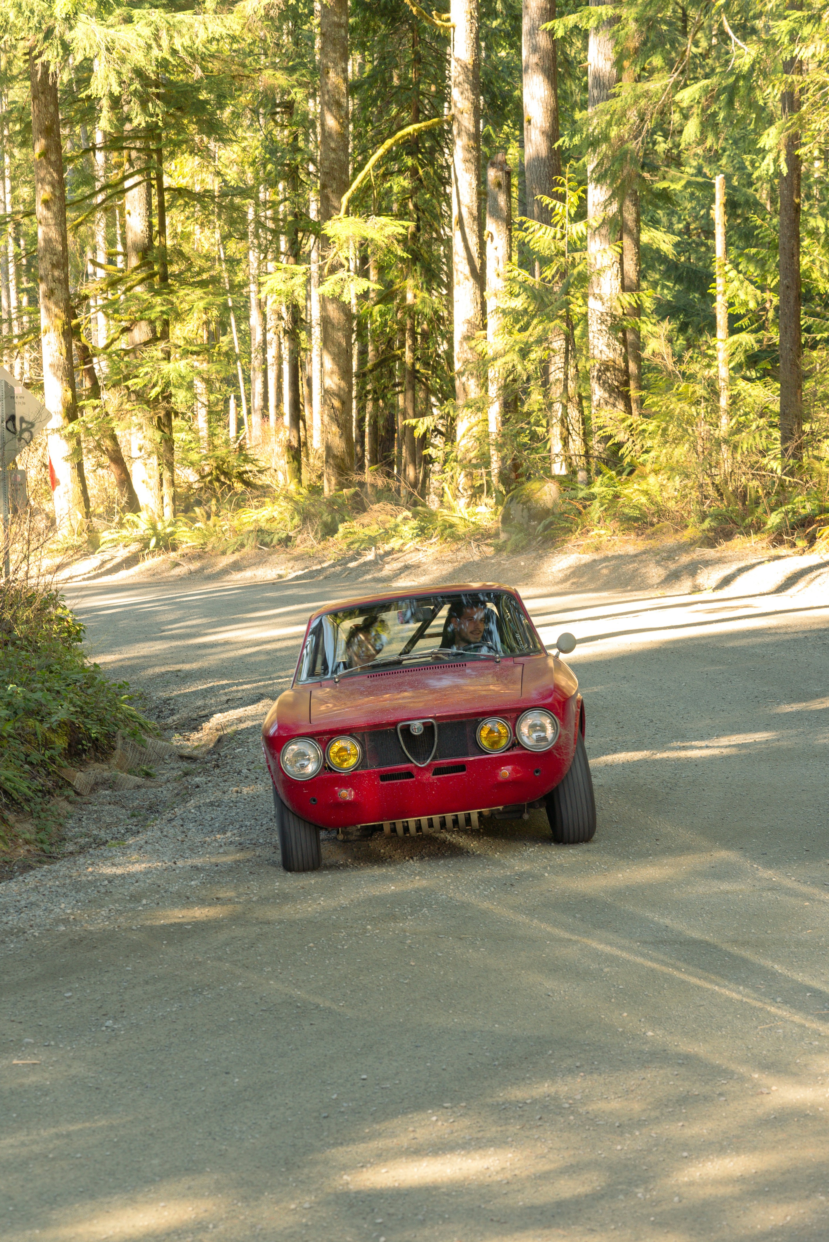 a red car driving down a dirt road