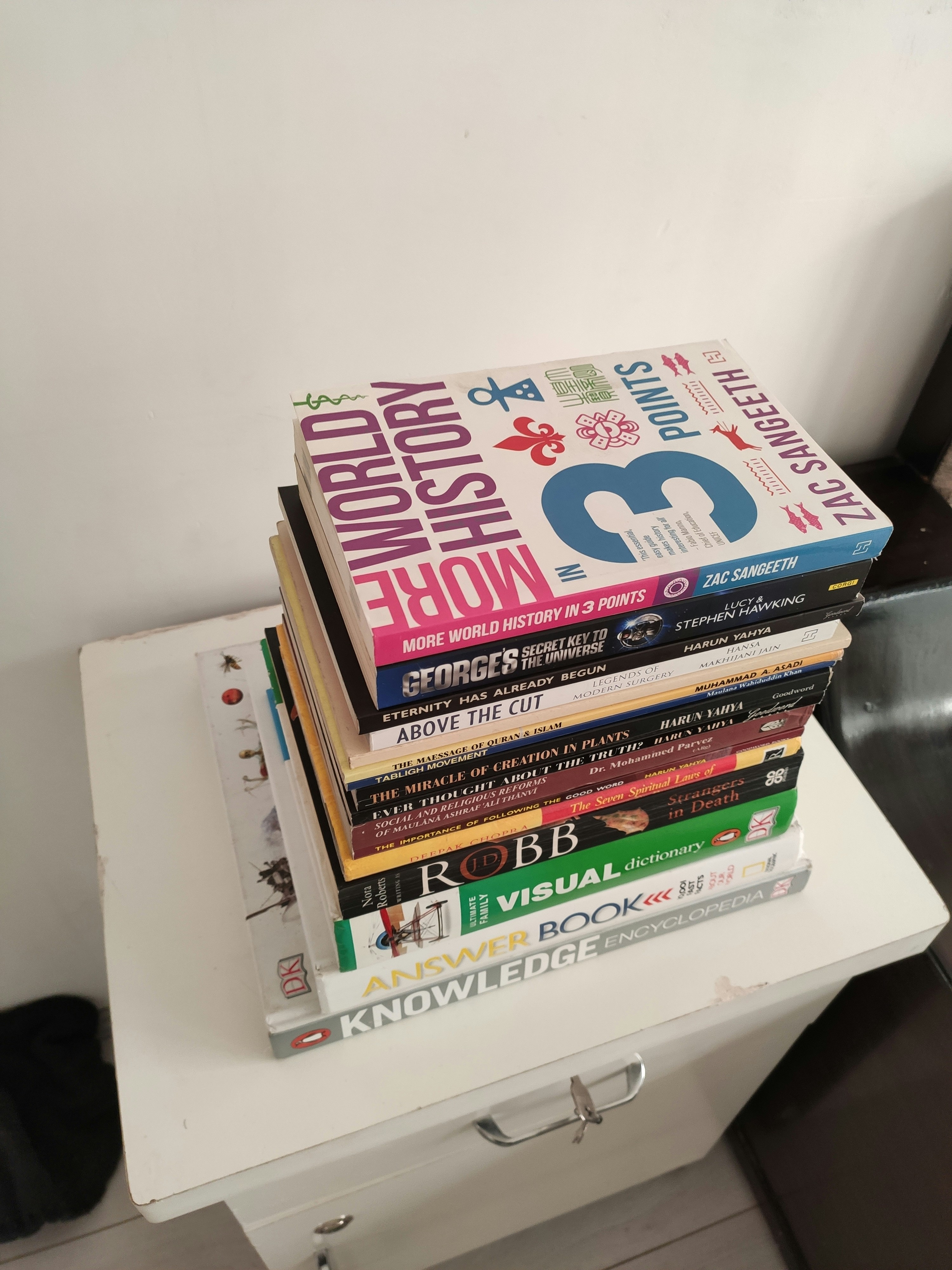 Colorful books stacked on bright white surface, clean editorial photography