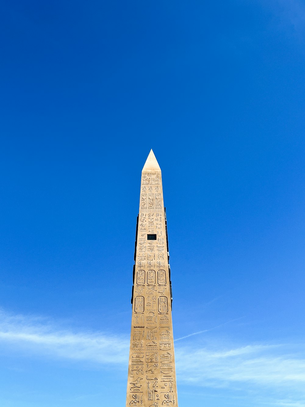 a tall obelisk with writing on it against a blue sky