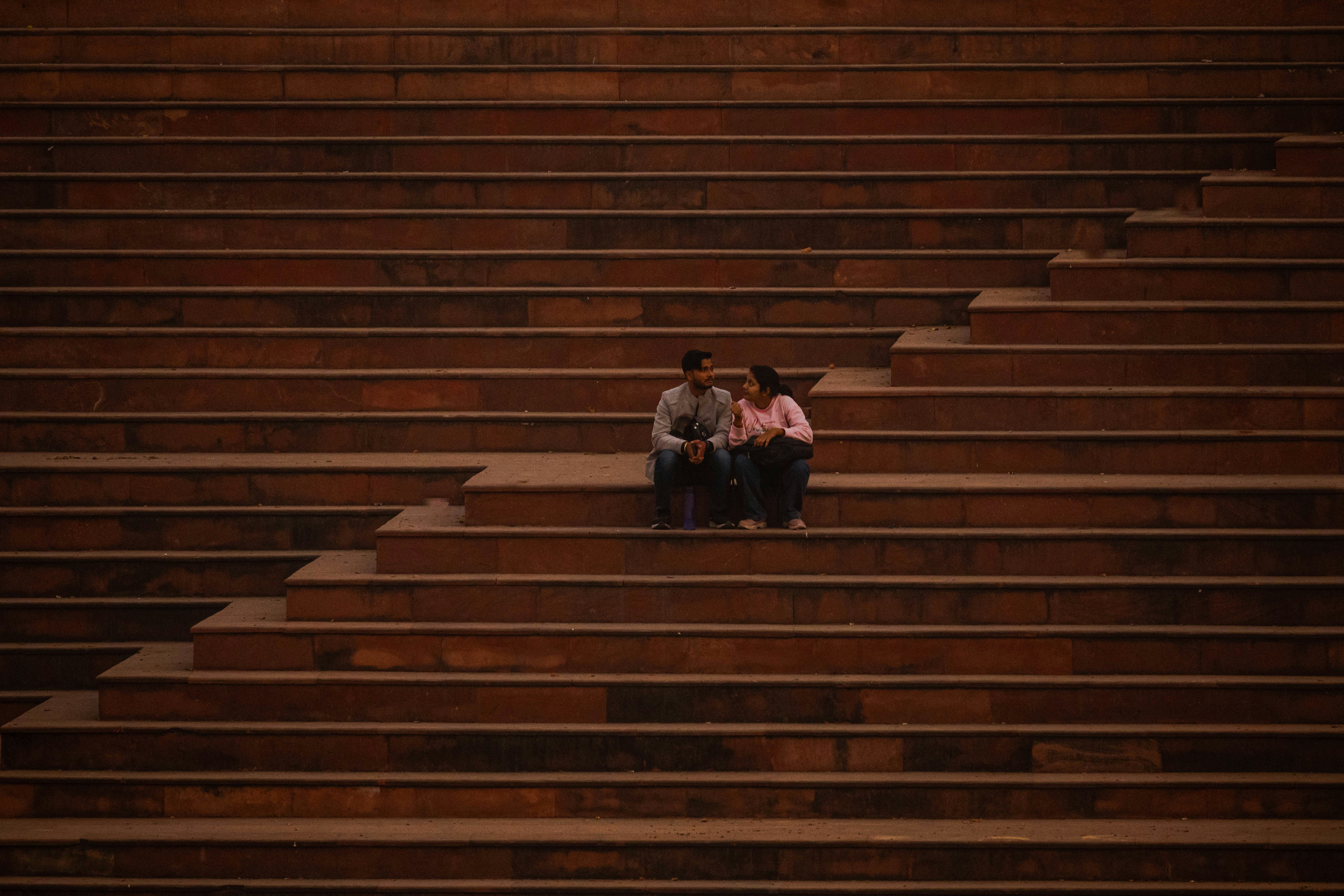 Two people sitting on the steps of a stadium photo – Free Human Image ...